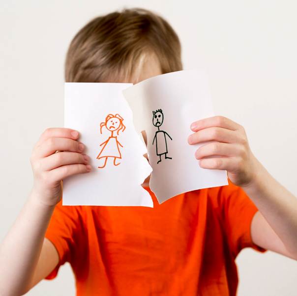 Enfant déchirant une feuille sur laquelle sont dessinés des personnages