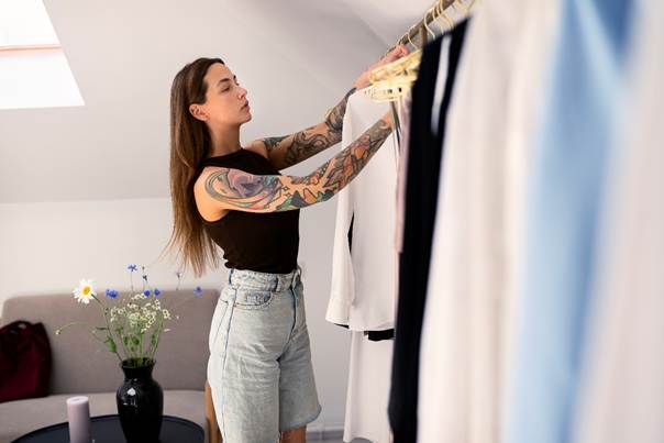 Femme tatouée choisissant une tenue dans une garde-robe