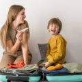 Une mère et son enfant faisant leur valise. La mère joue avec un avion en modèle réduit pour illustrer un départ en vacances