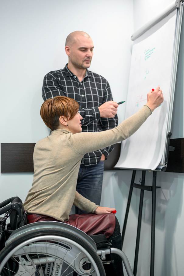 Image d'une personne en fauteuil roulant sur son lieu de travail collaborant avec une personne debout