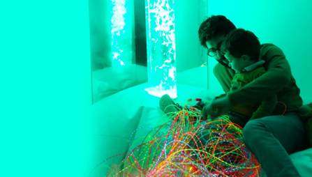 Un homme et un enfant jouent dans un espace Snoezelen