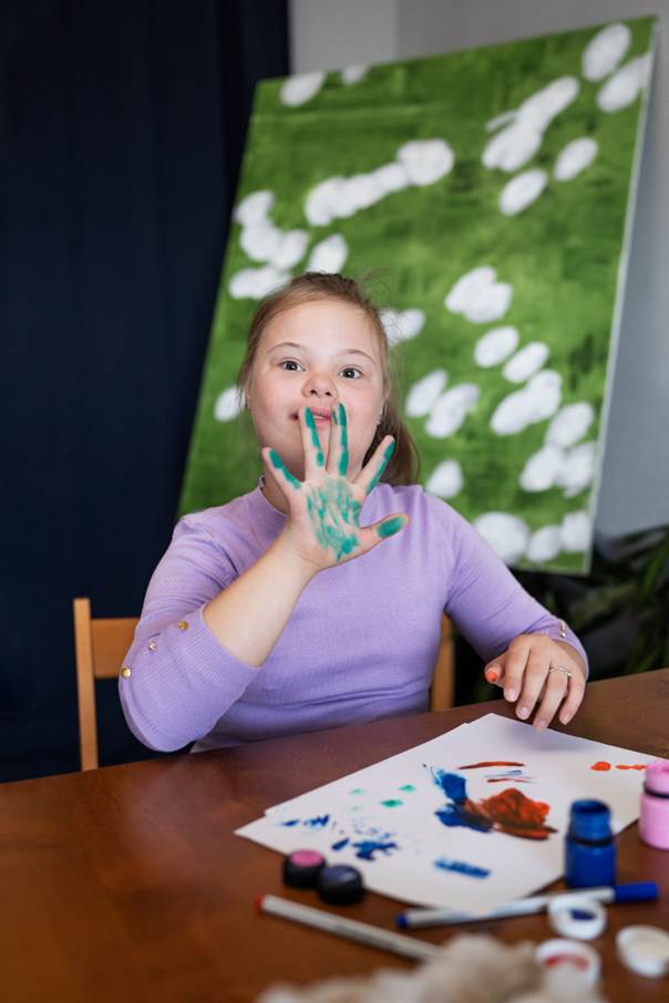 Photo d'une enfant T21 en classe faisant de la peinture