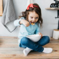 Petite fille qui mange son petit déj sur une table