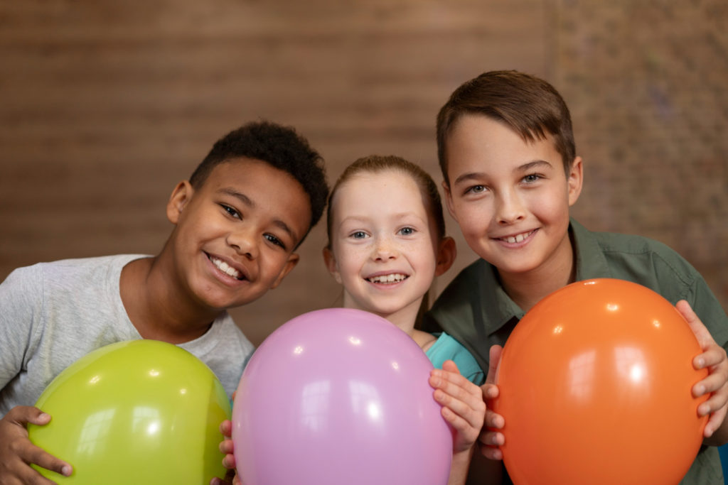 3 enfants avec chacun·e un ballon dans les mains