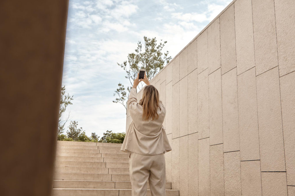 Femme prenant en photo le ciel devant un bâtiment apaisant