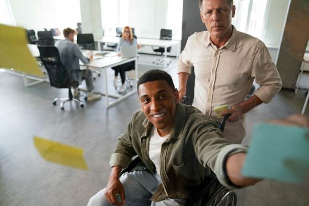 Deux personnes au travail, l'une d'entre elles est en fauteuil roulant