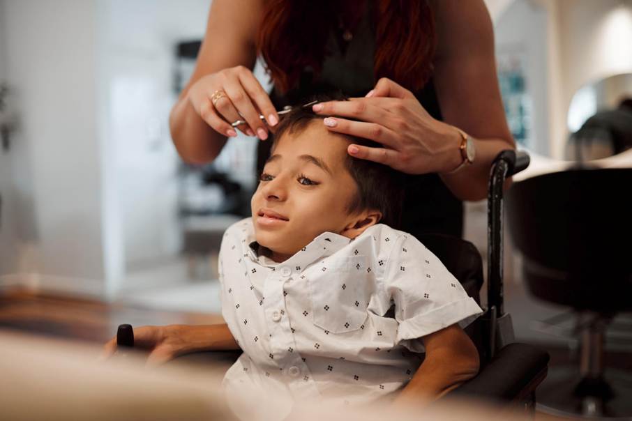 Enfant en situation de handicap en train de se faire couper les cheveux