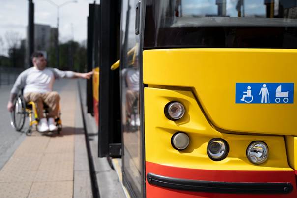 Avant d'un bus avec pictos accessibilité avec une personne en fauteuil roulant en arrière-plan