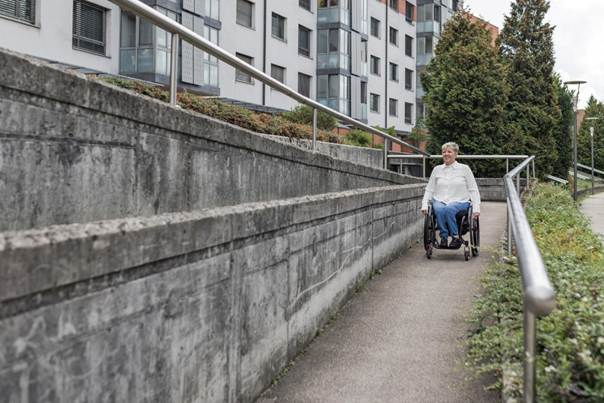 Personne en fauteuil roulant sur une rampe d'accès urbaine