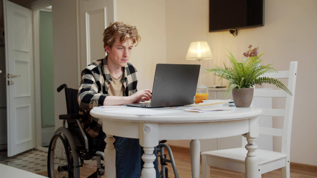 Homme en fauteuil roulant devant un ordinateur portable