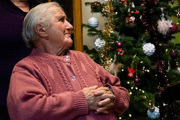 Dame âgée devant un sapin de Noël