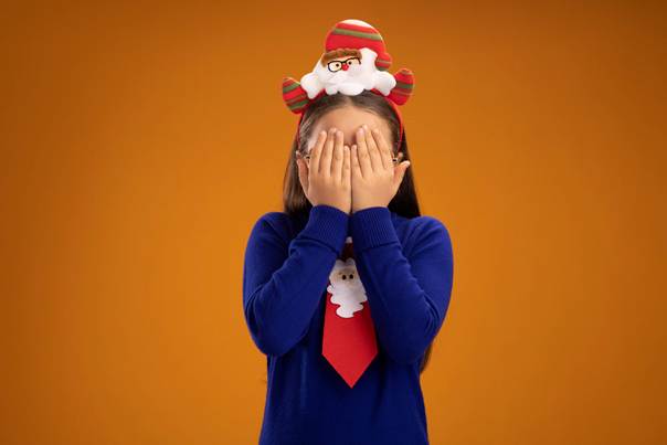 Enfant se cachant le visage en habits de noël
